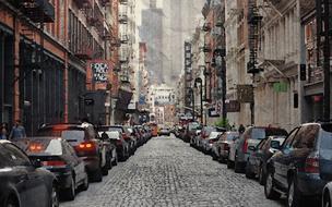 cars are parked along the road on a narrow street in new york