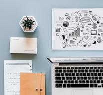 notepad, laptop and potted plant on the table