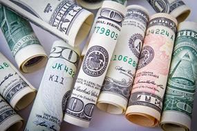 Rolls of the colorful dollar banknotes, with the numbers, on the white surface