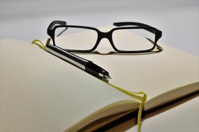 Notebook and Glasses on the white surface