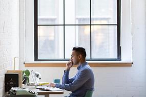 young man working on laptop at the table by the window