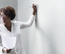 black girl writes on a whiteboard