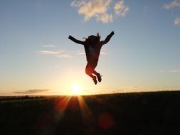Jumping woman and sunshine on the landscape