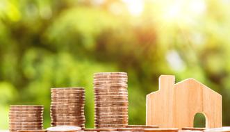 stacks of Coins and wooden toy house
