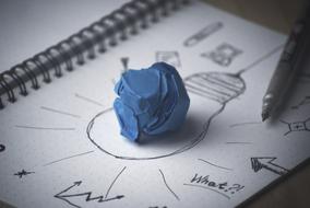 Creativity, blue paper ball on drawing with light bulb