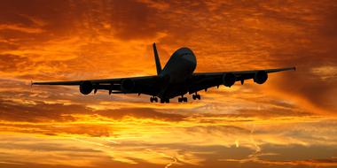 photo of a flying plane against a fiery sky