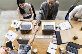 Agreement, top view of men shaking hands at table