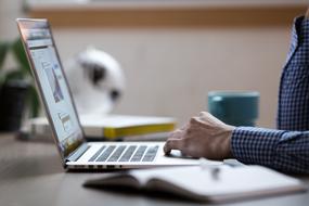 a man in a plaid shirt works on a laptop