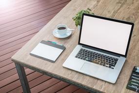 laptop, graphic tablet and cup of coffee on the table