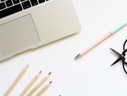 Pencils and laptop computer at white surface