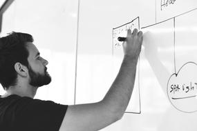 young caucasian man writes on white Board