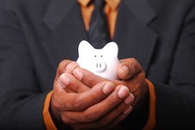 white piggy bank in the hands of a businessman