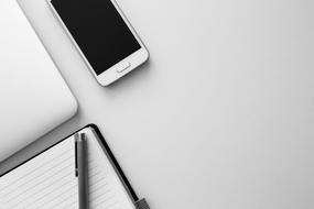 black and white photo of a smartphone lying near a laptop