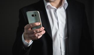 Businessman in black and white suit, using shiny smartphone