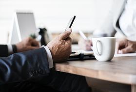 white cup of coffee on an office table on a blurred background