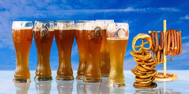 Beer glasses with foam near the pretzels and sausages on Oktoberfest in Bavaria, Germany