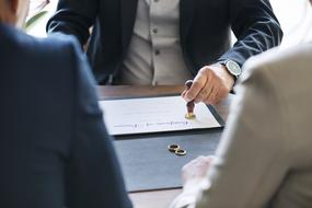 man puts stamp on certificate of divorce and wedding rings on table