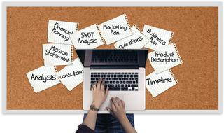 bulletin board with business word cloud and person at laptop