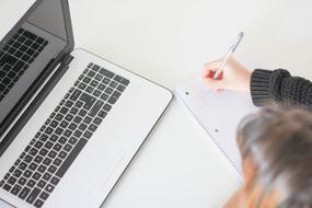 female person with pen at Macbook Laptop computer