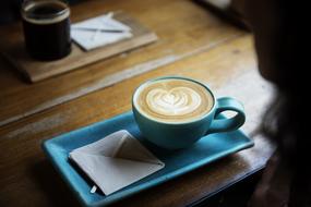 cup of coffee and an envelope on a saucer