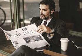 american businessman reading newspaper and drinking coffee