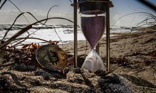 cryptocurrency and hourglass on the beach
