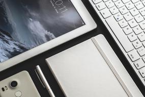 tablet, notepad, pen, smartphone and keyboard on the table