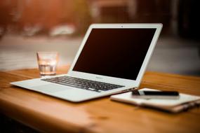 white laptop, notebook and glass of water on the table