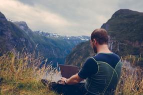 guy working on laptop in the mountains