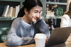 Smiling, Asian woman using laptop in the cafe