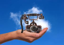 vintage phone in hand against sky background