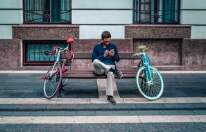 man with smartphone on a bench in city street