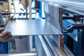 Person, using tube bender, with the shiny board, on the factory