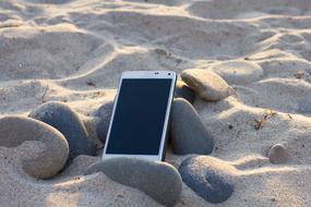 Cell phone on the stones in the sand