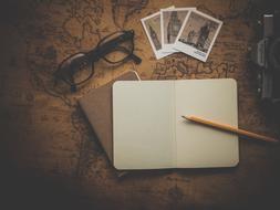 notebook, pencil, vintage postcards and glasses on the table