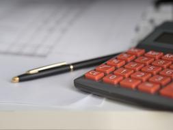Business Calculator with red buttons near the black pen