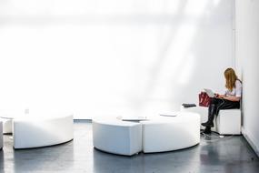 Girl with laptop, sitting in the corner of the room with white furniture