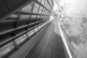 black and white photo of an office building tower under the clouds