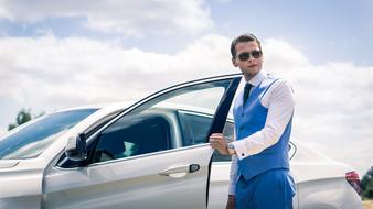 businessman in blue suit opens car door