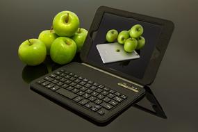 fresh green apples and an image of apples on a laptop screen