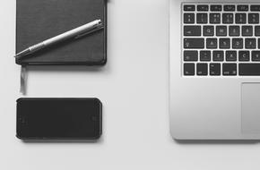 monochrome photo of laptop, notebook, pen and smartphone