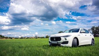 Beautiful white car on the green grass on landscape