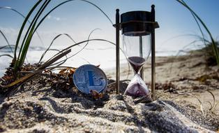 Cryptocurrency and Hourglass on sand beach