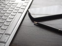 smartphone lies near the laptop on the table