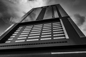 Black and white photo of the glass building and cloudy sky
