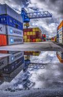 stack of shipping Containers in Port mirroring on puddle