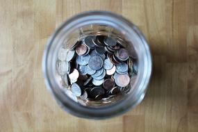 coins in glass jar on the wooden surface