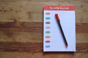 red Pen and Note Paper on the wooden surface