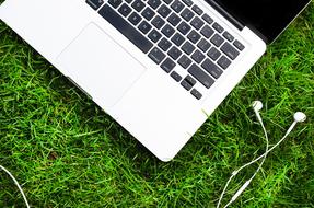 Headphone and laptop on green grass