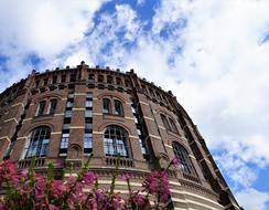 Beautiful Gasometer and purple flowers in Vienna, Austria, at blue sky with white clouds on background